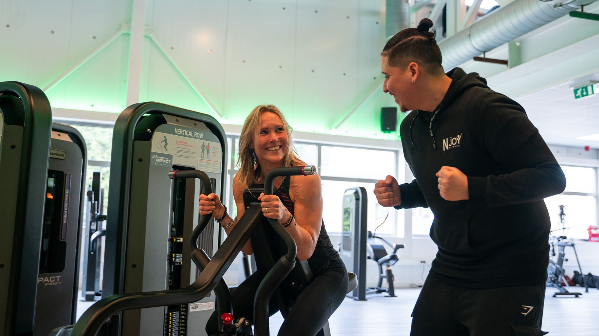 Een sportschool vol met fitnessapparatuur en televisies.