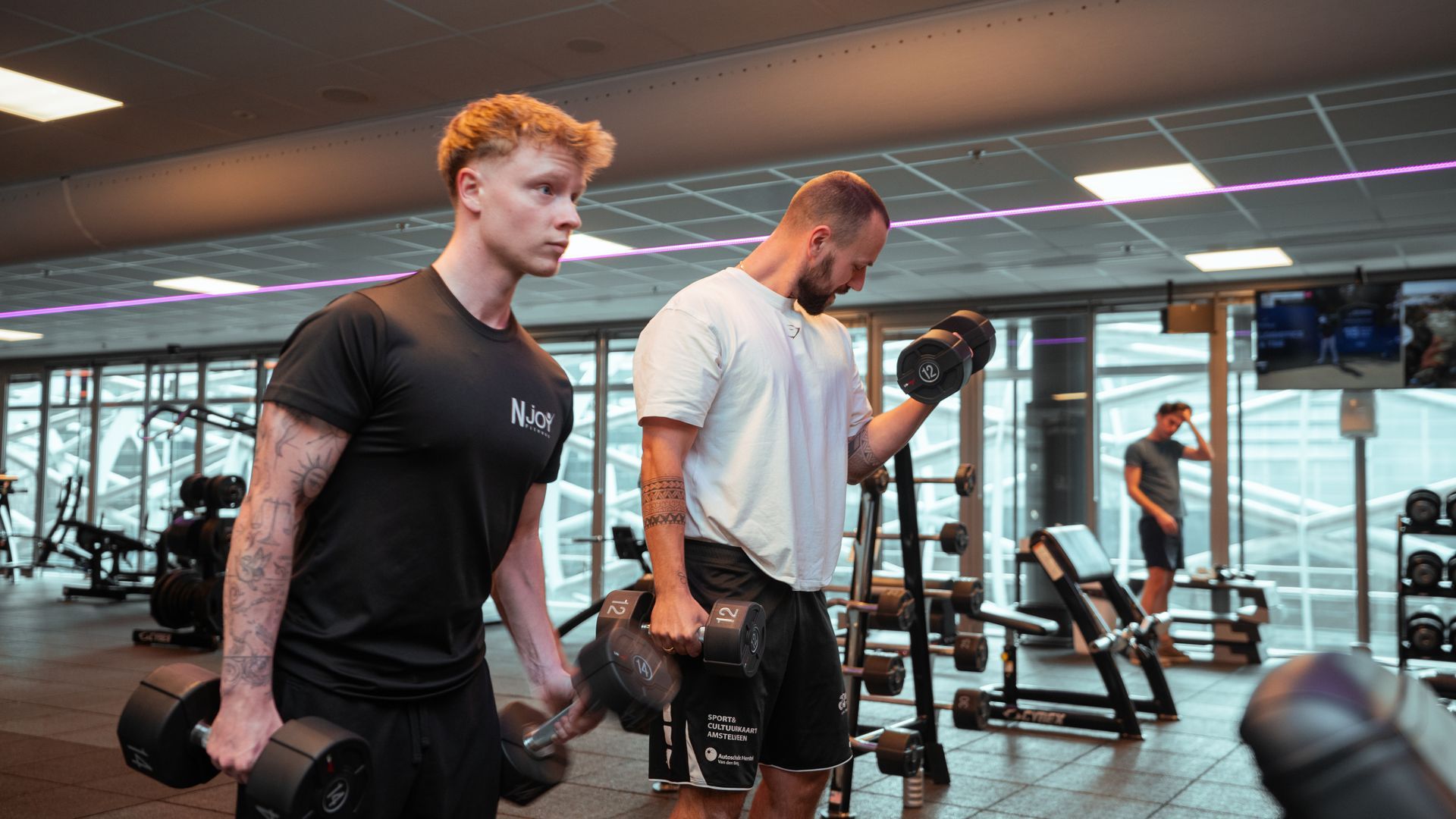Een sportschool vol met fitnessapparatuur en paarse lichten.