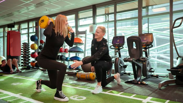 Een sportschool met veel apparatuur en een neonbord met de tekst 'kracht'.