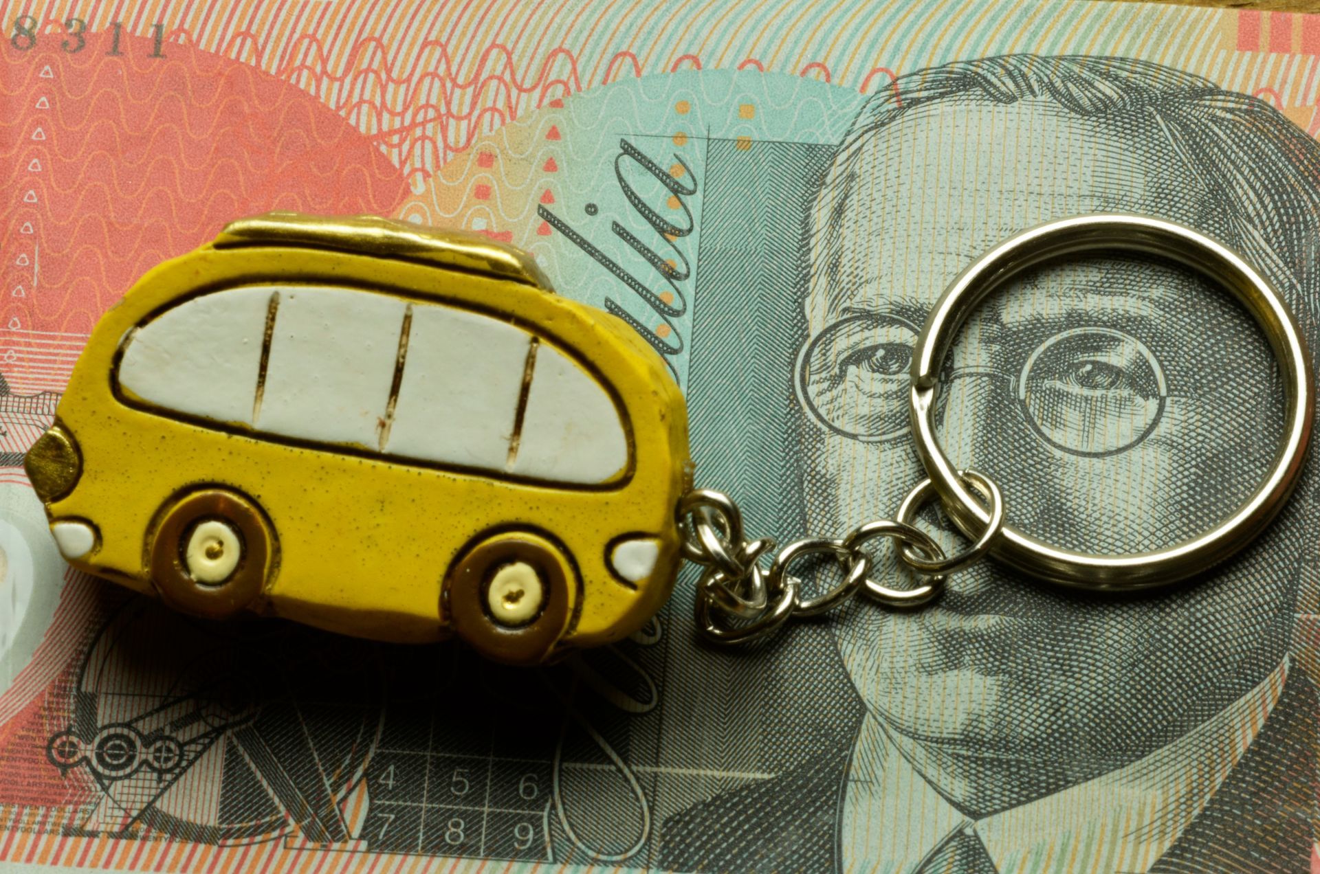 Yellow bus keychain on a banknote background