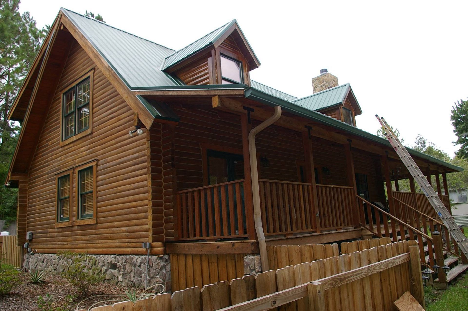 Rustic wooden cabin with a porch and stone foundation in a wooded setting