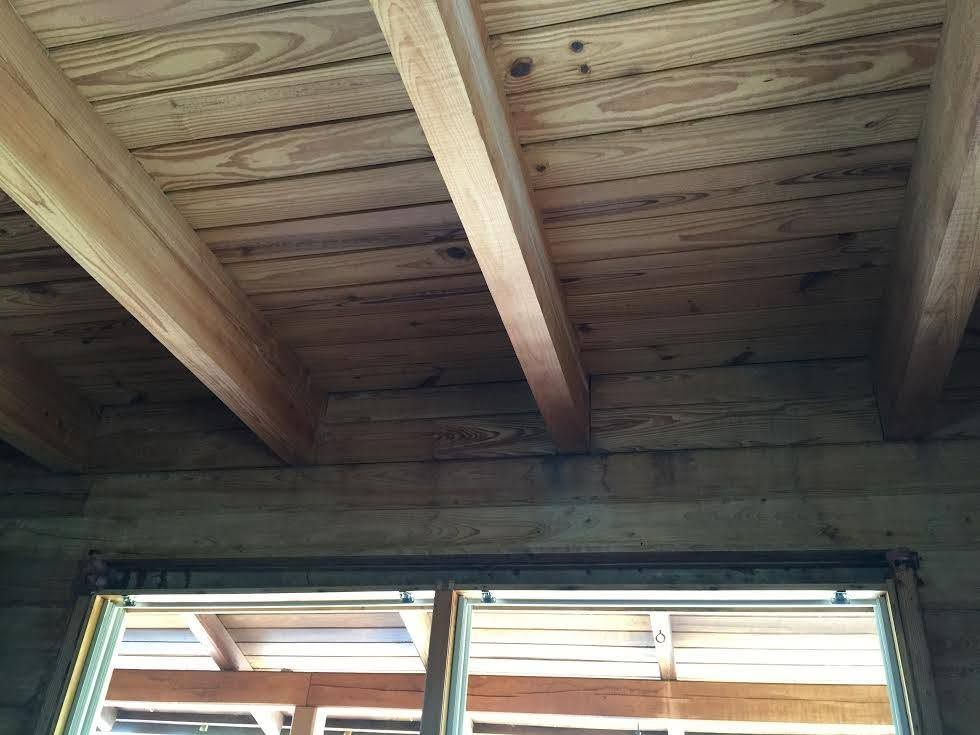 Wooden plank ceiling with exposed beams above a doorway or window opening.