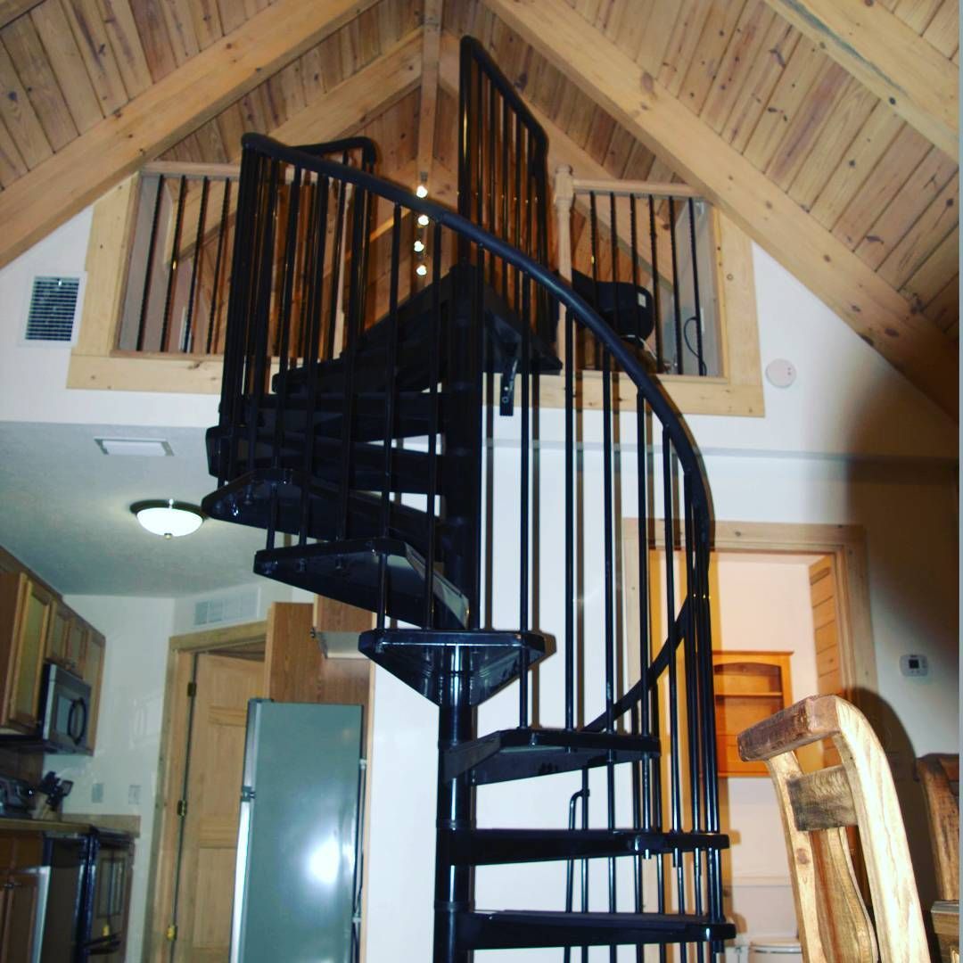 Black spiral staircase in a wood-paneled loft interior