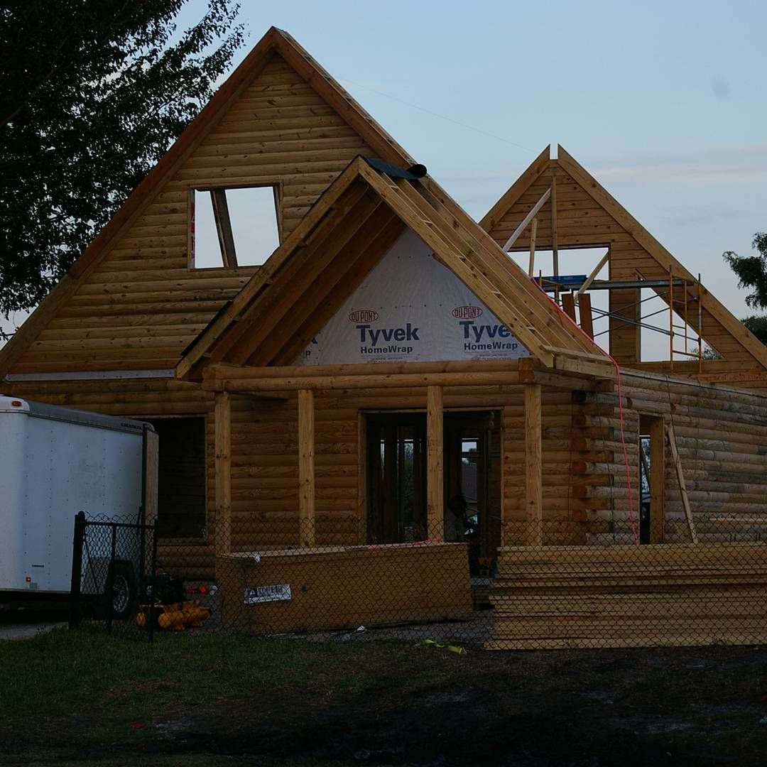 Partially built wooden house with exposed framing and roof trusses at dusk