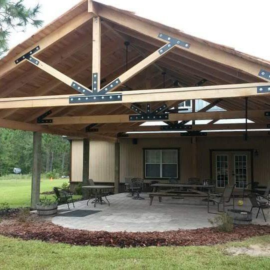 Covered patio with wooden trusses, patio furniture, and a house exterior in the background