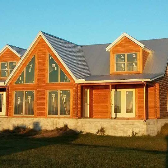 New wooden house with a gray roof and large windows in warm sunlight