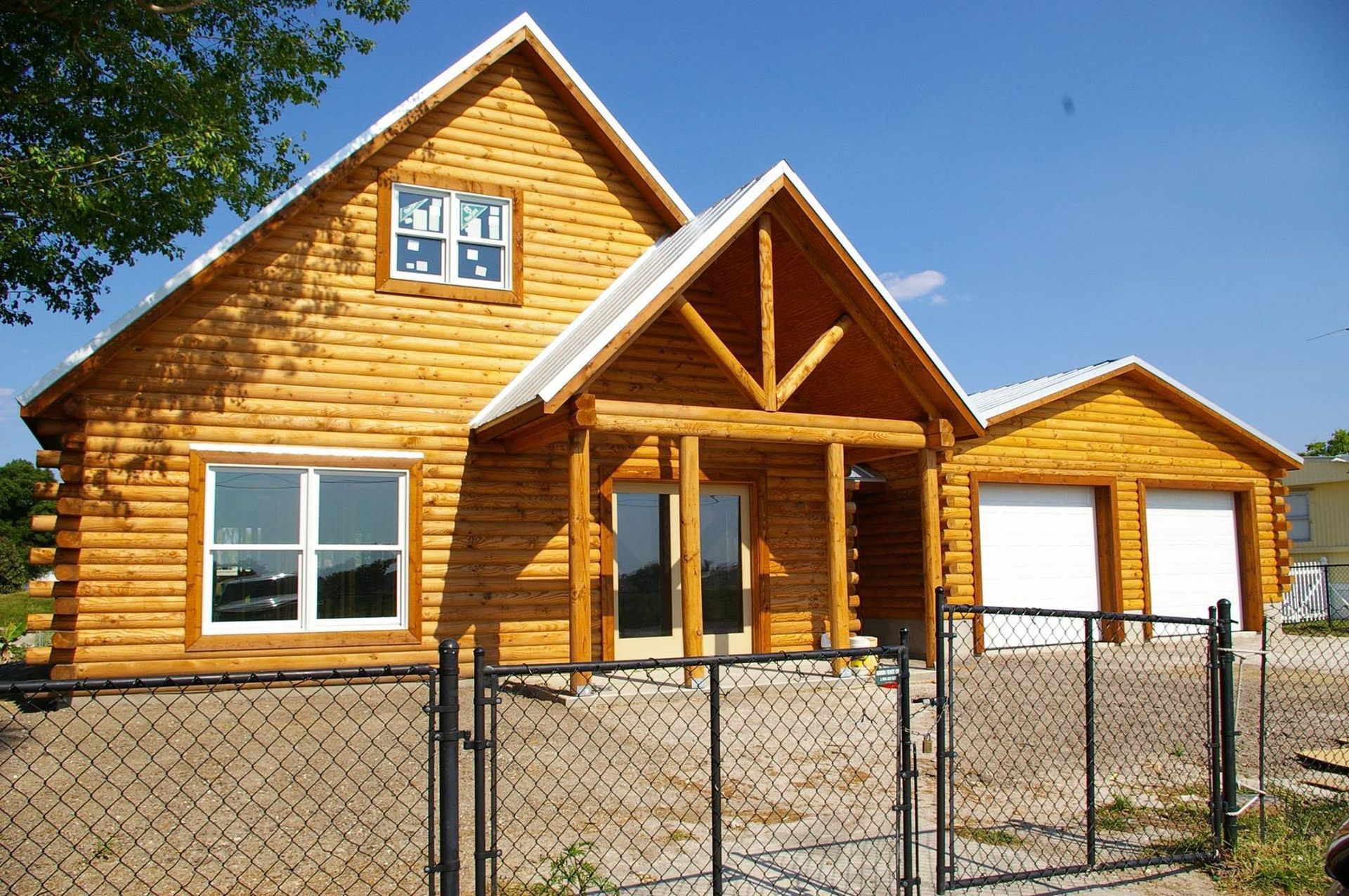 Wooden house under construction with a chain-link fence in front
