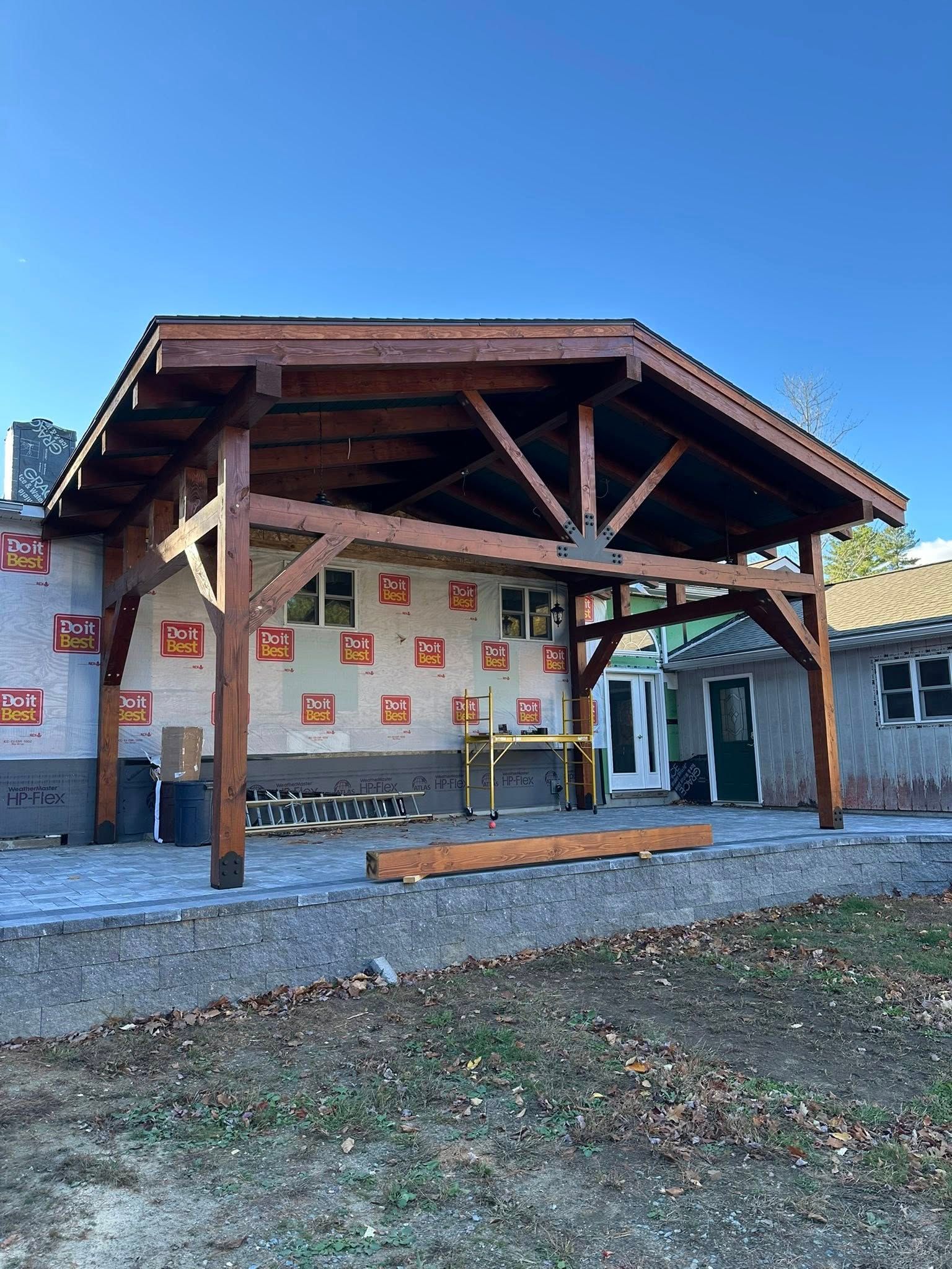 Rustic wooden pavilion with stone walls and orange accents under a clear blue sky