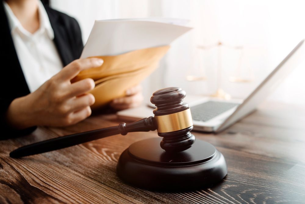 Gavel on Desk, With Person Holding Papers and Laptop — Umbrella Legal in Lake Macquarie, NSW