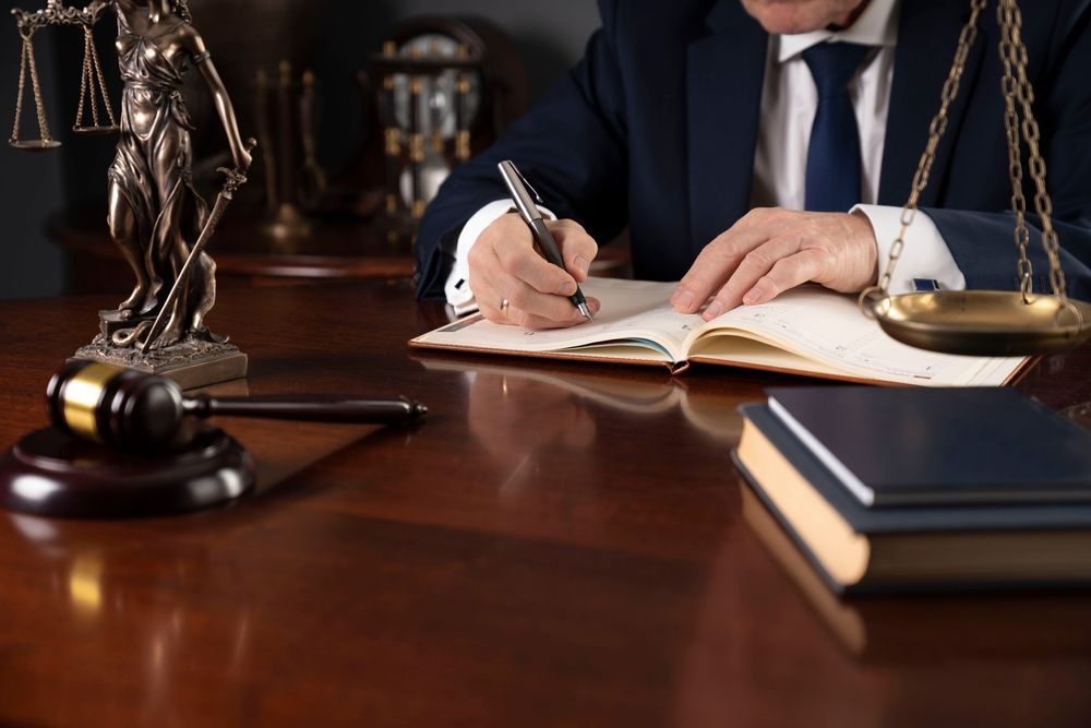 Lawyer in Suit Writing in a Book, Scales of Justice, Gavel on Wooden Desk — Umbrella Legal in Cardiff, NSW