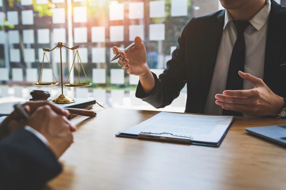 Lawyer Discussing Documents With a Client at a Desk — Umbrella Legal in Cardiff, NSW