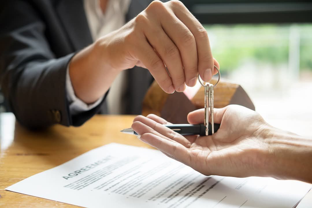 Person Handing Keys to Another Person — Umbrella Legal in Cardiff, NSW