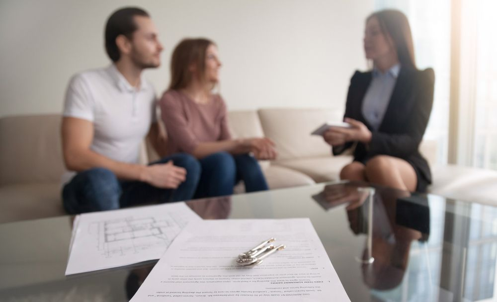 A Couple Sits on a Couch While a Professional Explains Documents — Umbrella Legal in Cardiff, NSW