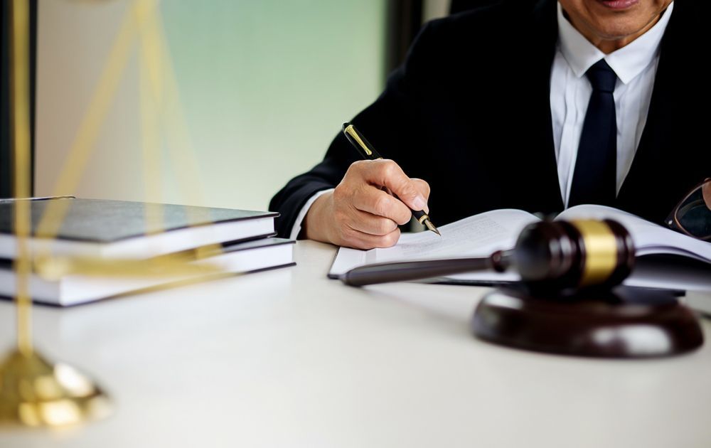Lawyer in a Suit Writing at a Desk With a Gavel and Scales of Justice — Umbrella Legal in Wyong, NSW