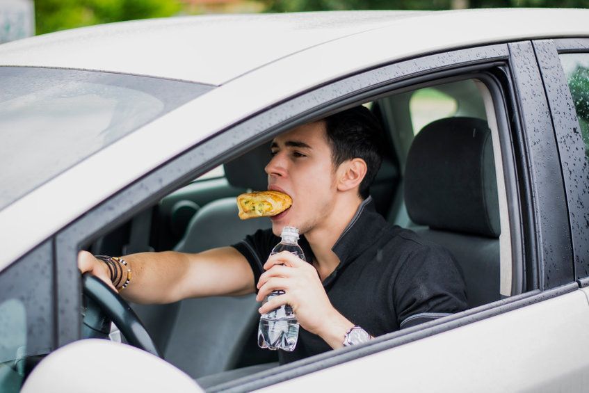 Man Eating Pizza and Drinking Water While Driving a Car — Umbrella Legal in Cardiff, NSW