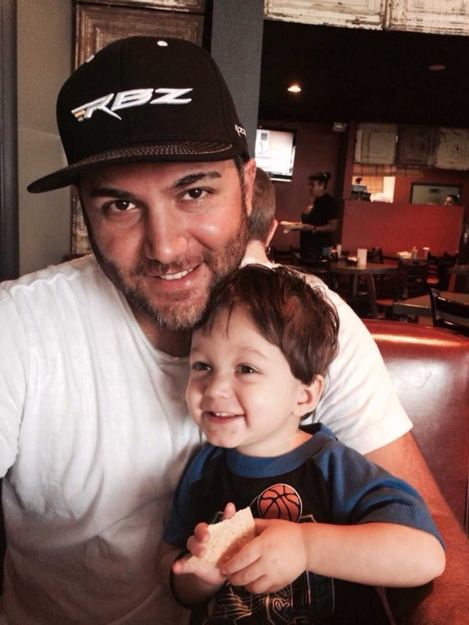 A man wearing a rpz hat is holding a little boy