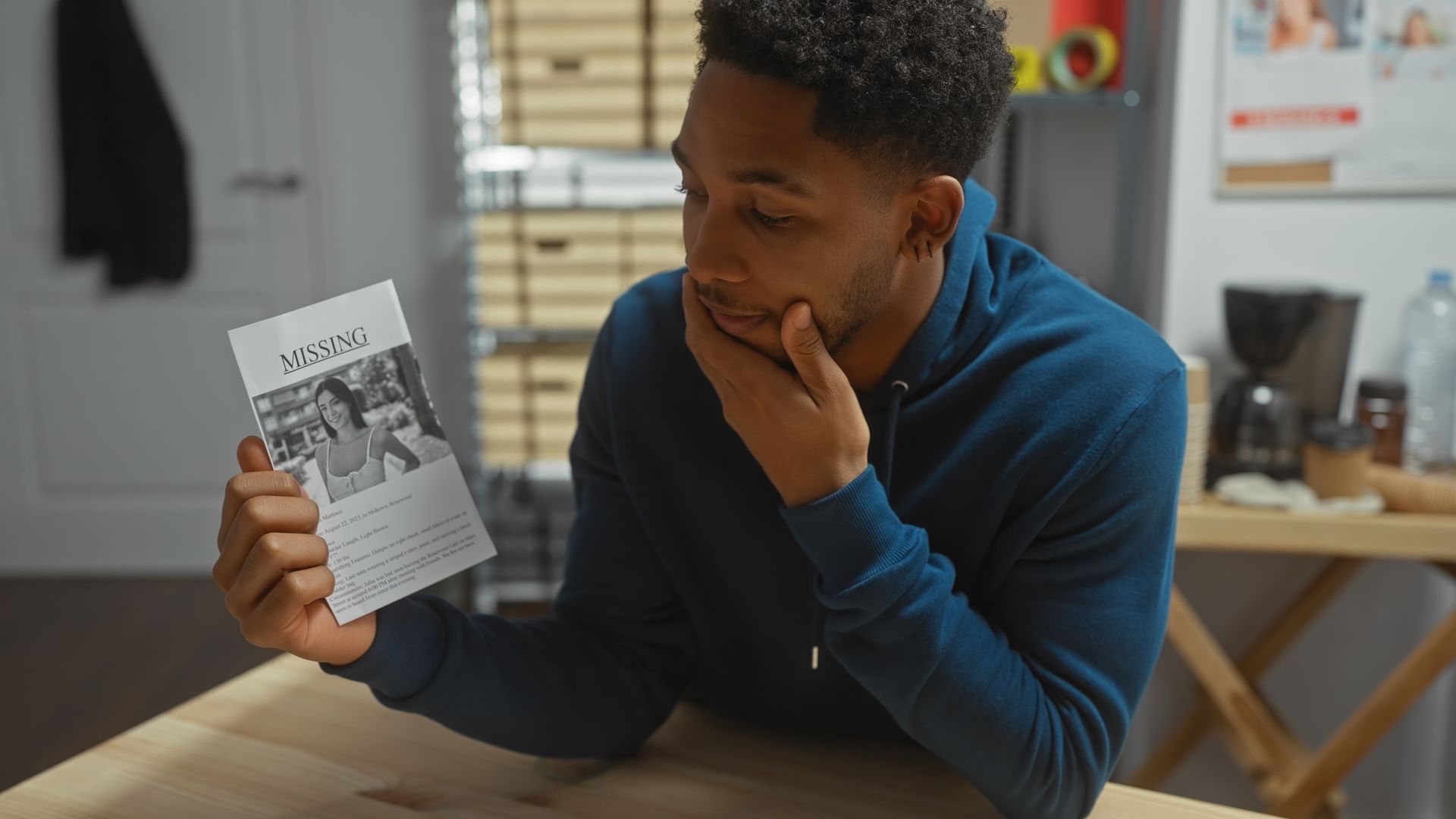 A man is sitting at a table holding a piece of paper.
