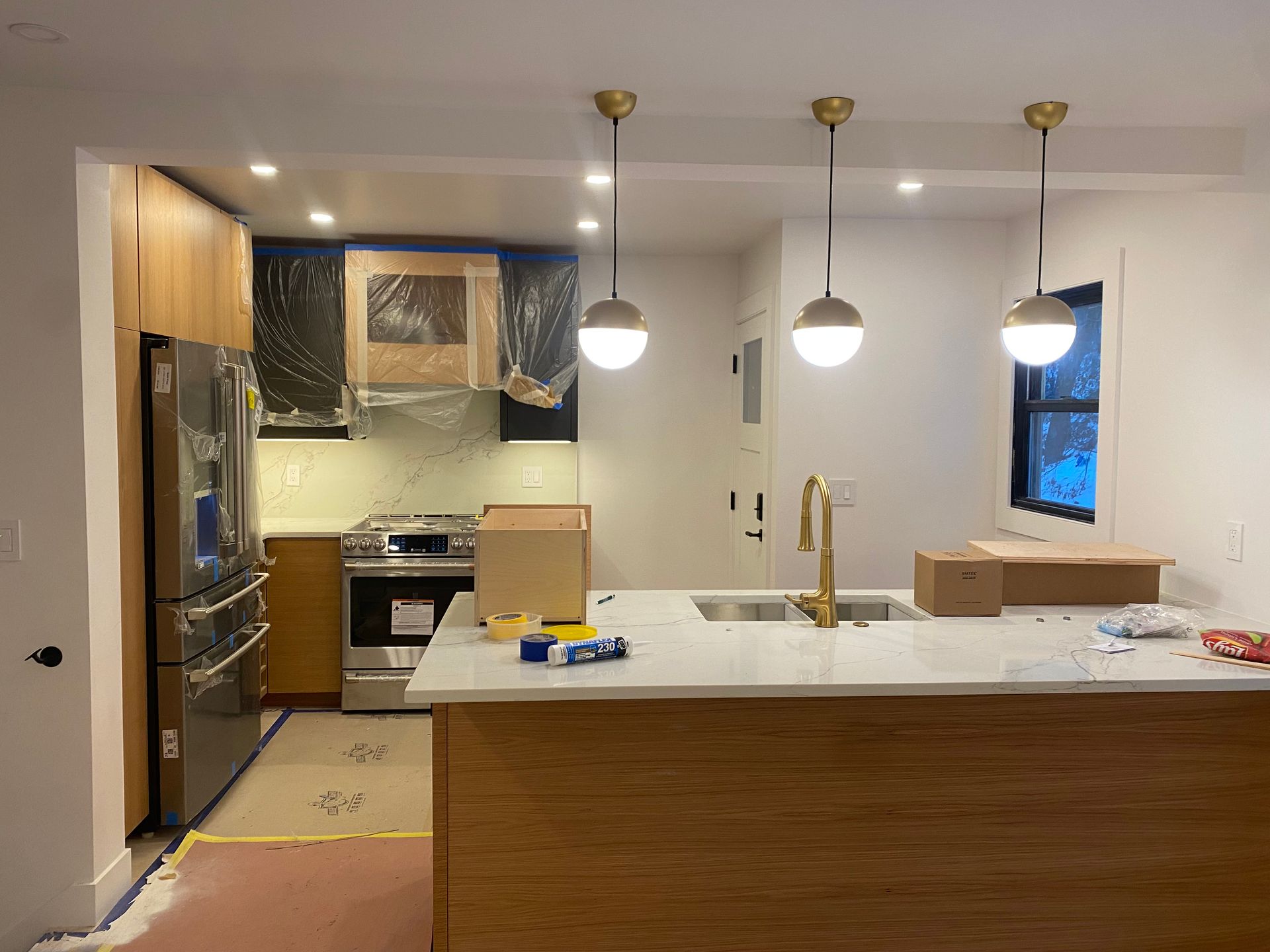 Modern kitchen with white island, wooden cabinets, stainless fridge, and three pendant lights