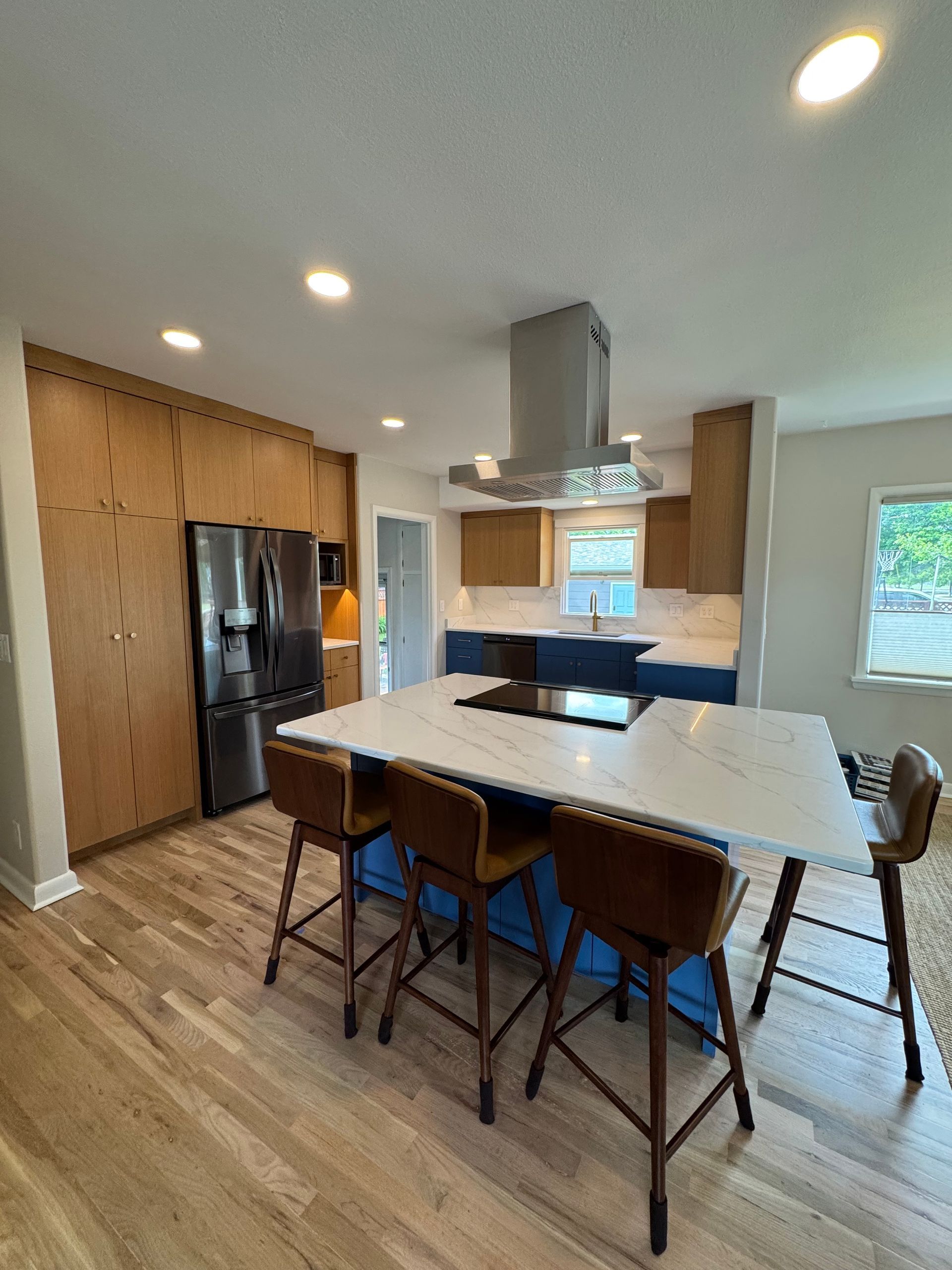 Modern kitchen with island, dining table, black fridge, and wood floors