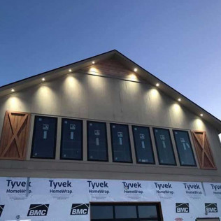 House gable under construction at dusk, with lit exterior and Tyvek house wrap