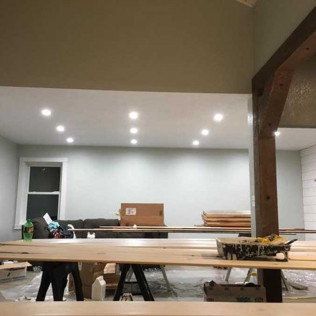 Interior of a room under renovation with recessed lights, exposed beams, and construction materials on sawhorses.