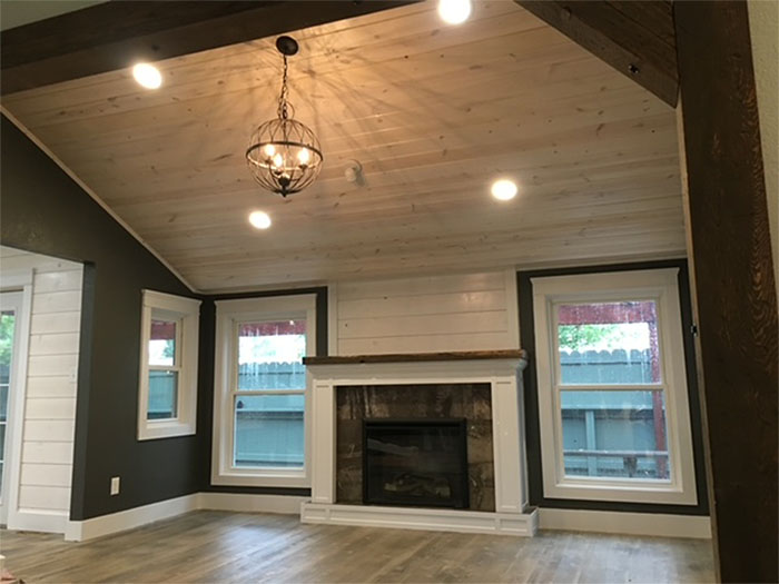 Living room with vaulted wood ceiling, chandelier, fireplace, and two windows