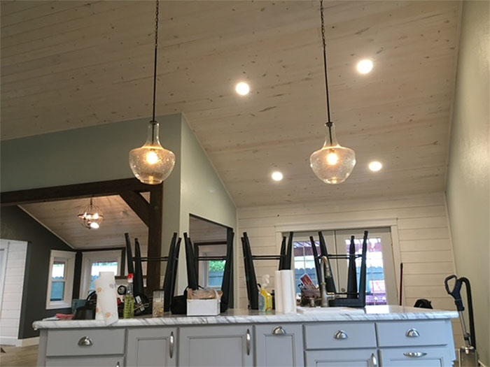 Modern kitchen with white cabinets, black pendant lights, and a vaulted ceiling with recessed lights