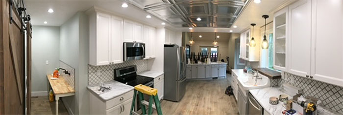 Bright white modern kitchen with gray island, stainless appliances, and pendant lights