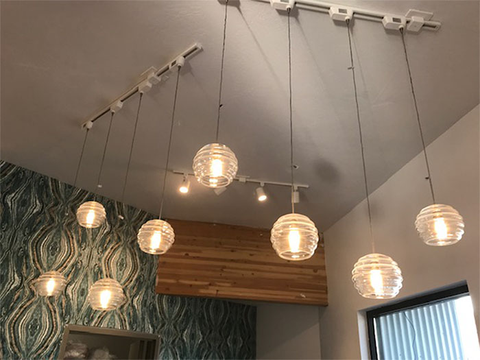 Hanging globe pendant lights above a café corner with patterned wall and window