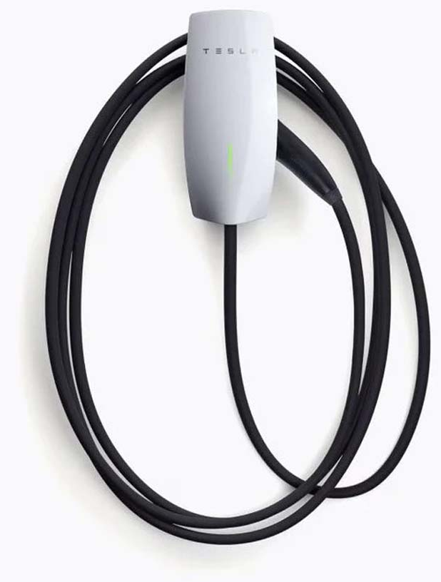 A white Tesla Wall Connector charging station mounted on a wall with its black charging cable coiled around it.