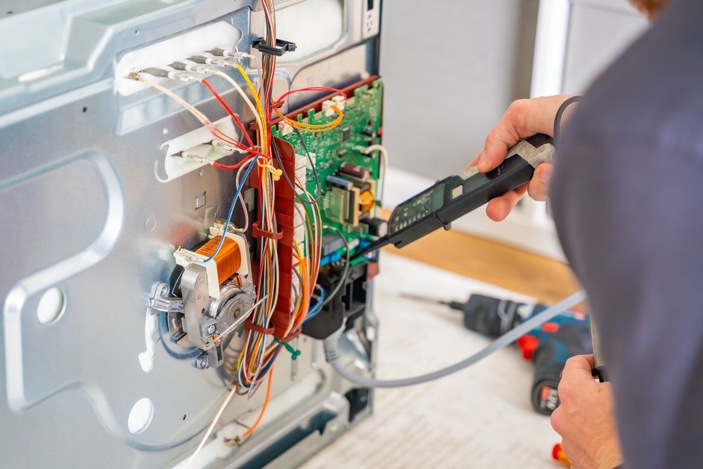 Technician testing exposed wiring inside a metal appliance with a multimeter