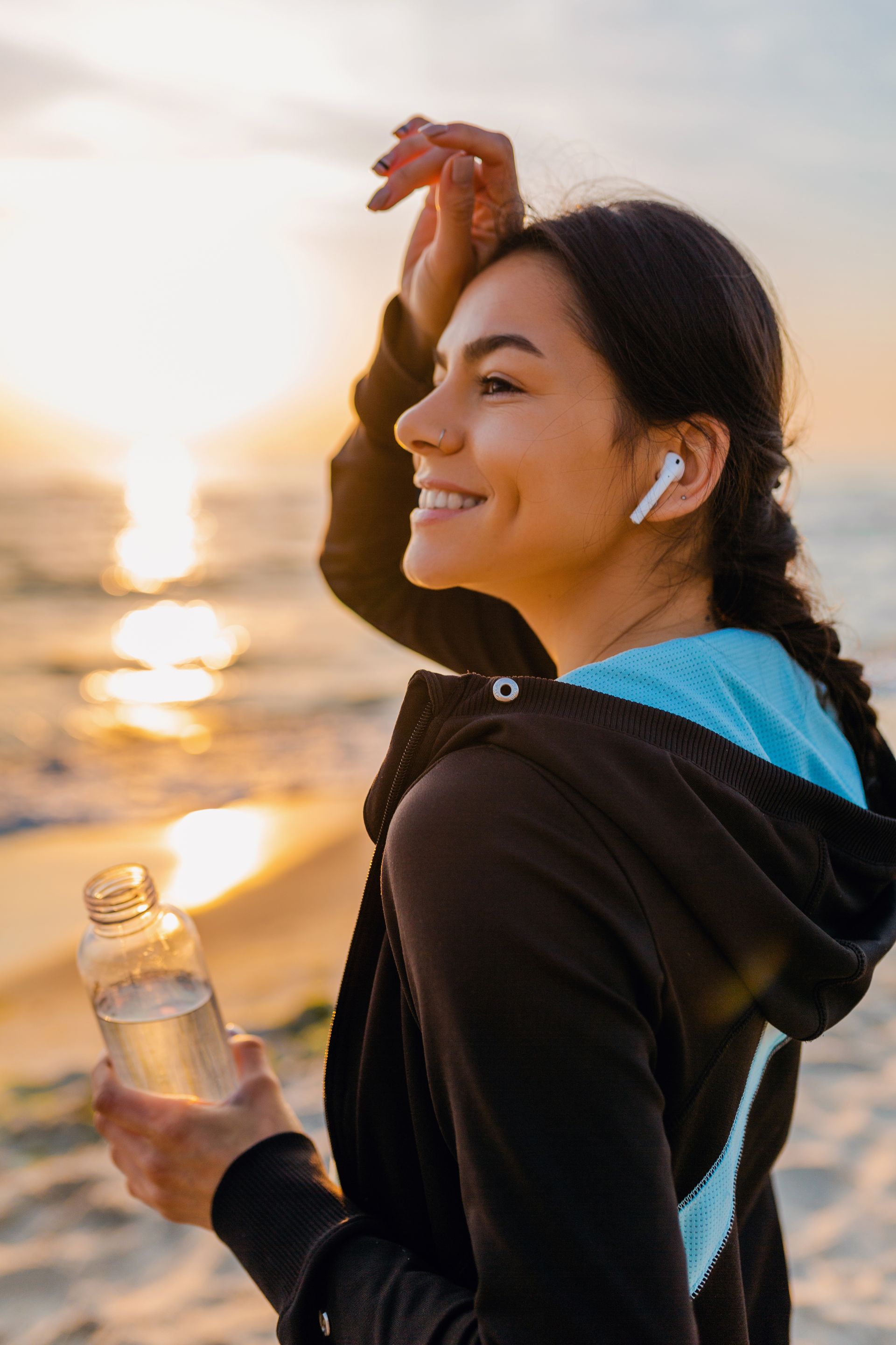 a woman is holding a bottle of water on the beach .