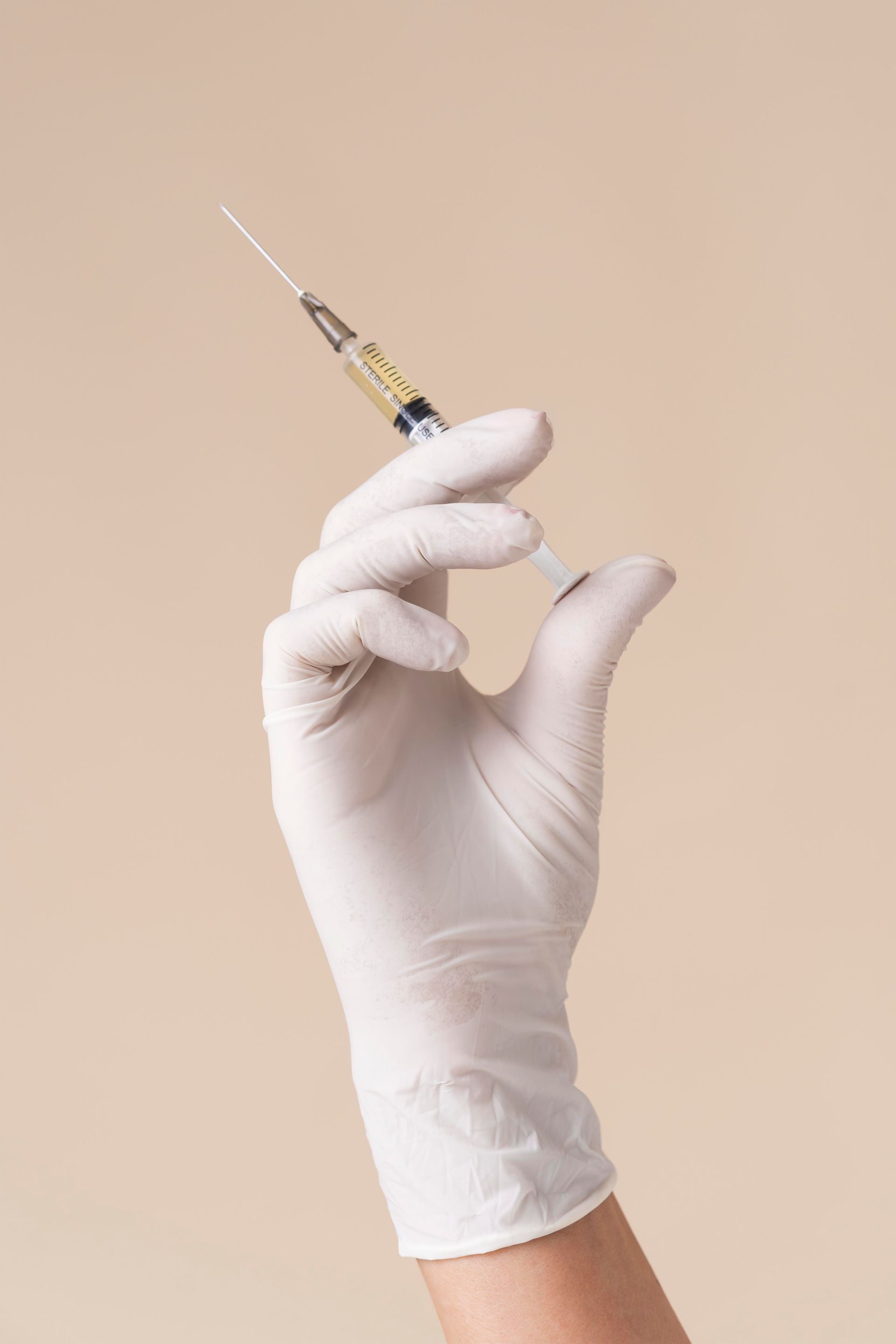 a hand in a white glove is holding a syringe .