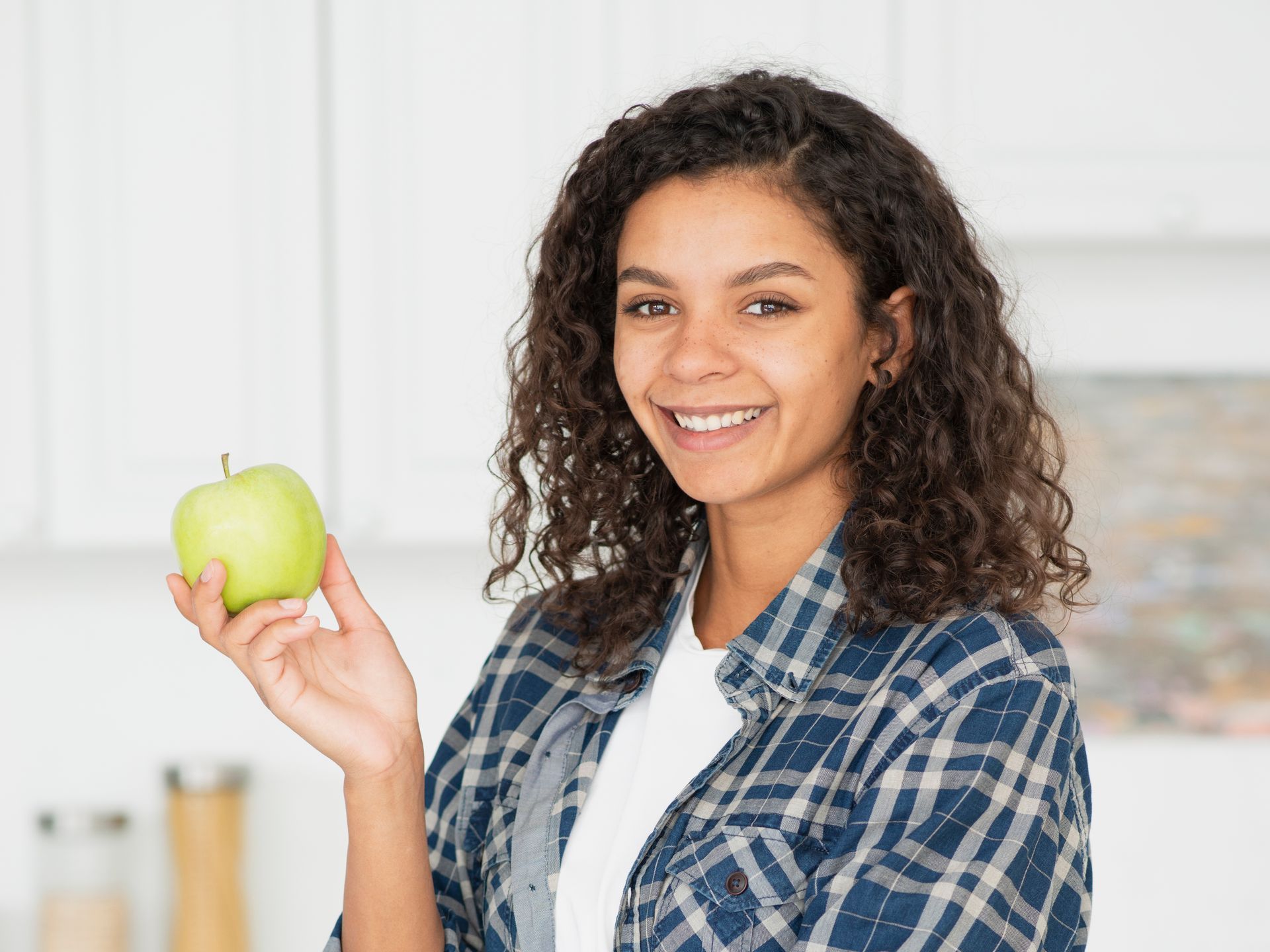 a young woman is holding a green apple in her hand .