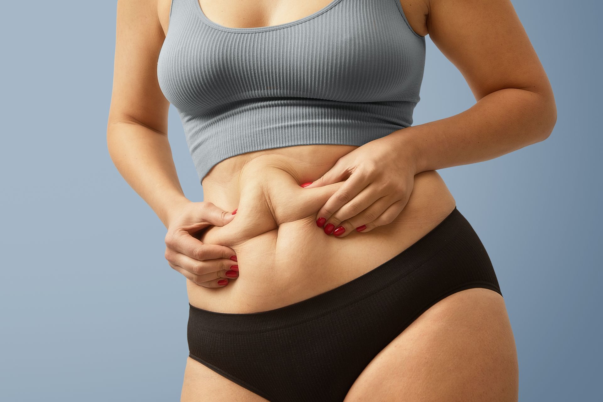 a woman in a bra and underwear is holding her stomach .