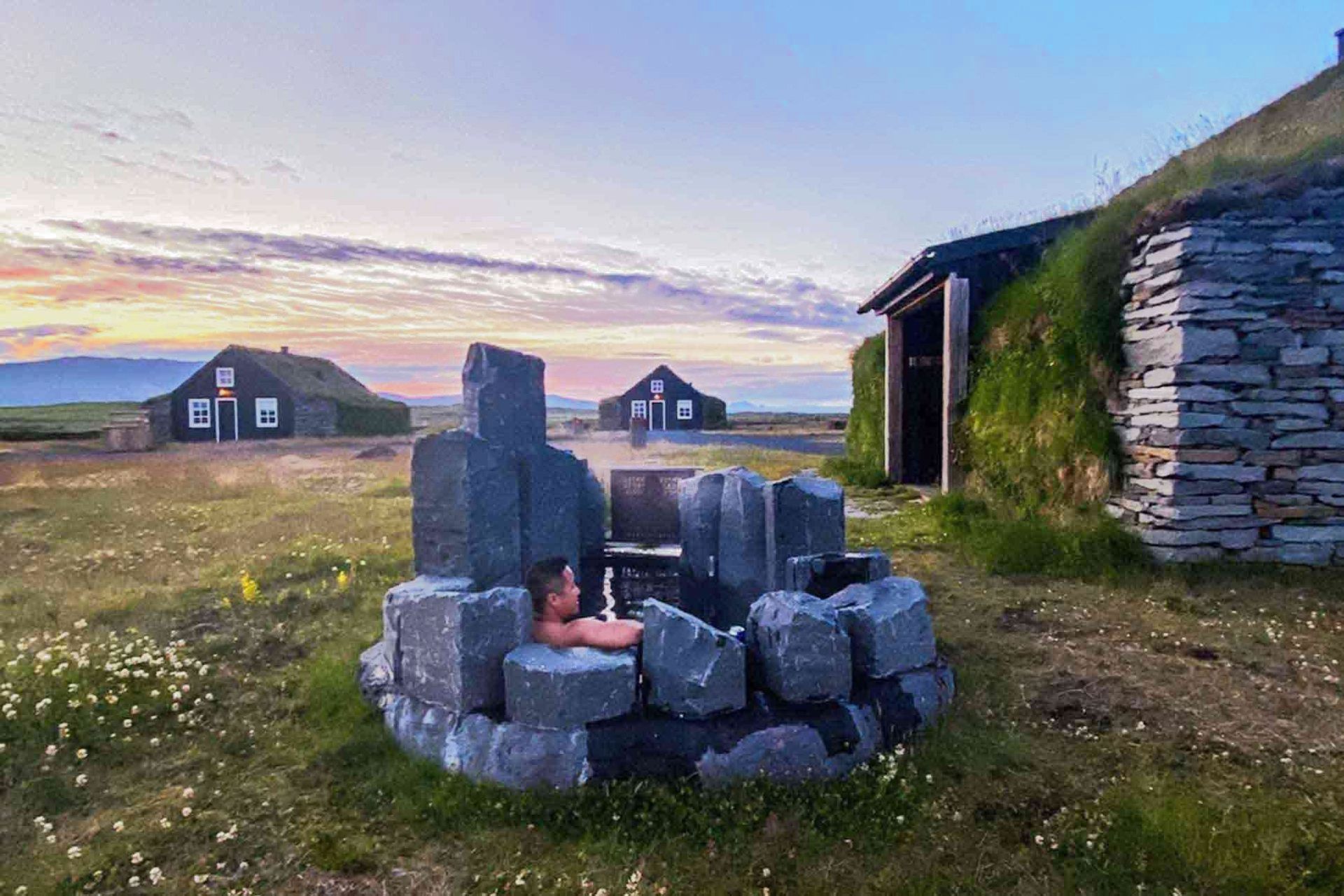 A man is laying in a stone bathtub in a field.