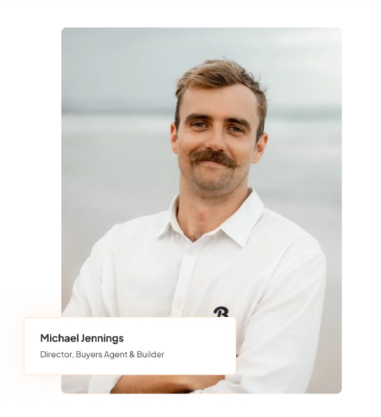 Michael Jennings, director, smiling in white shirt, arms crossed, with ocean background.
