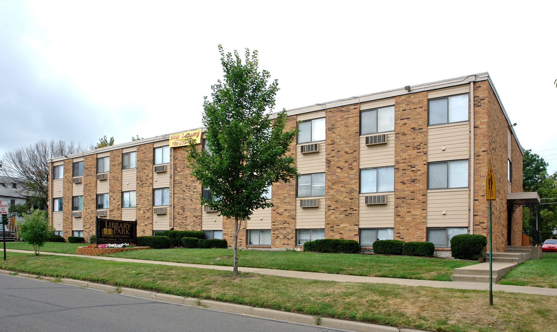 Multi-story brick apartment building with many windows and air conditioners.