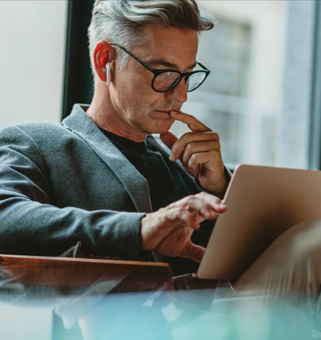 A man wearing glasses is using a laptop computer