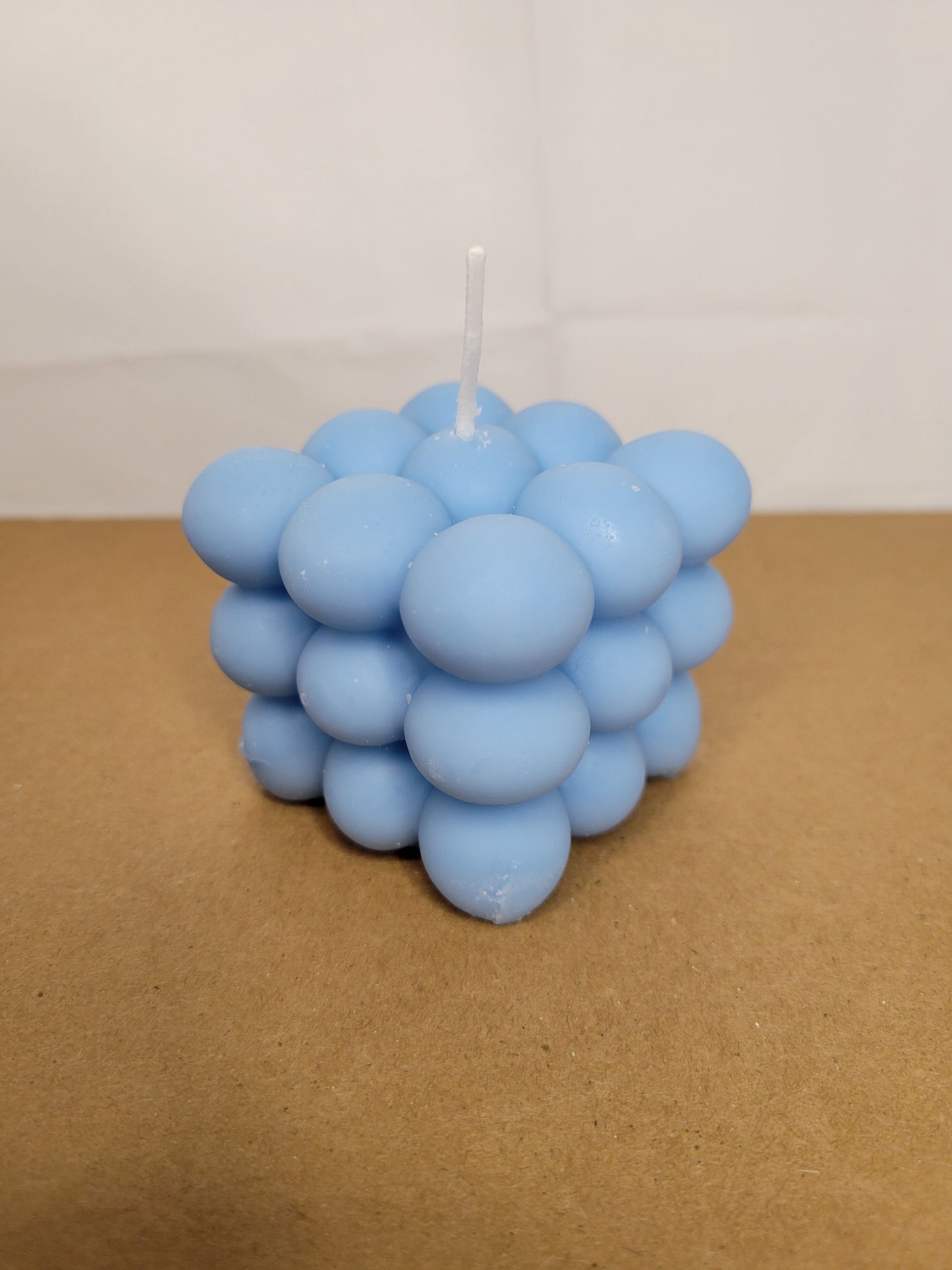 Light blue bubble candle on a brown surface against a plain beige background