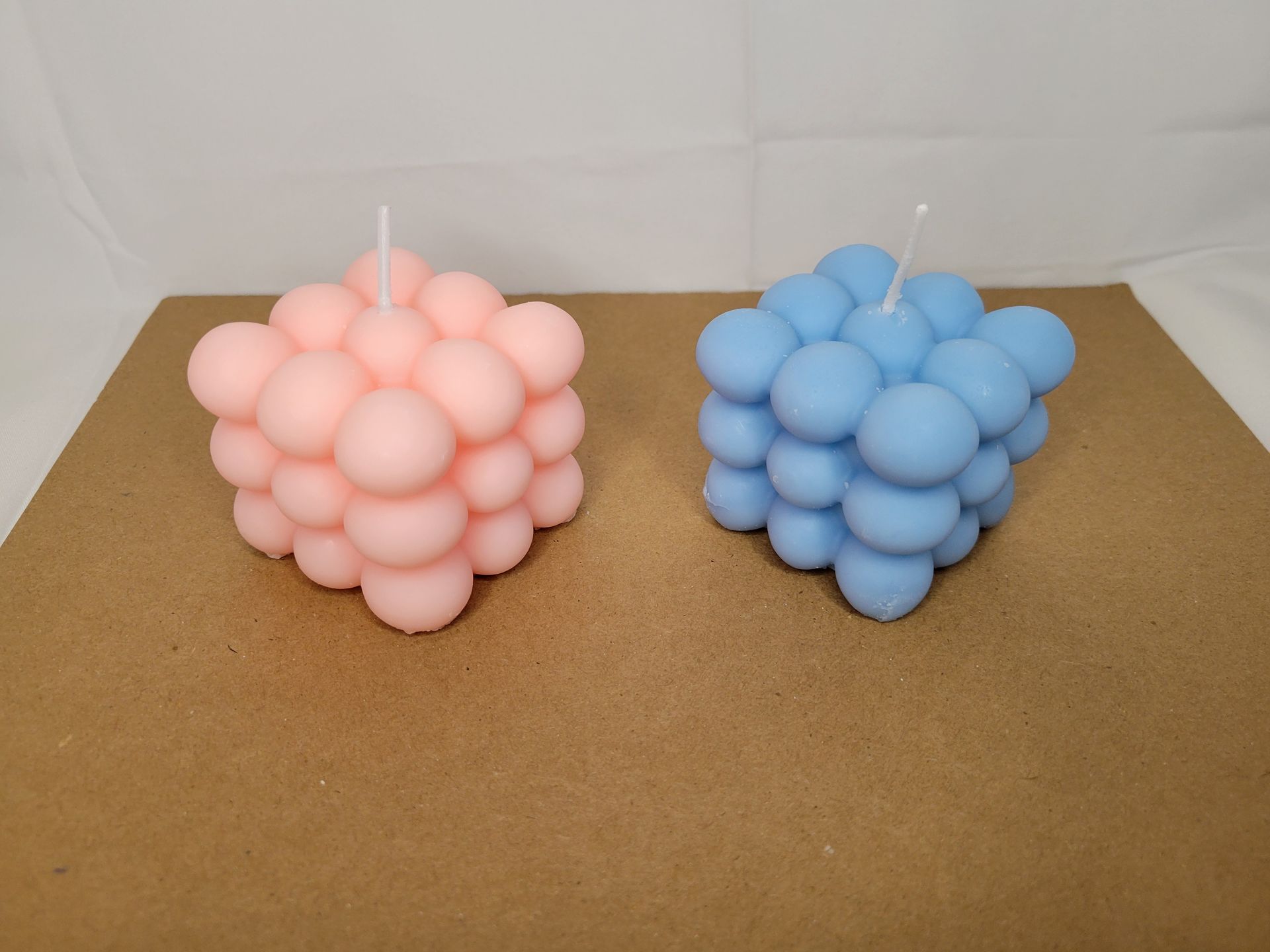 Light blue bubble candle on a brown surface against a plain beige background