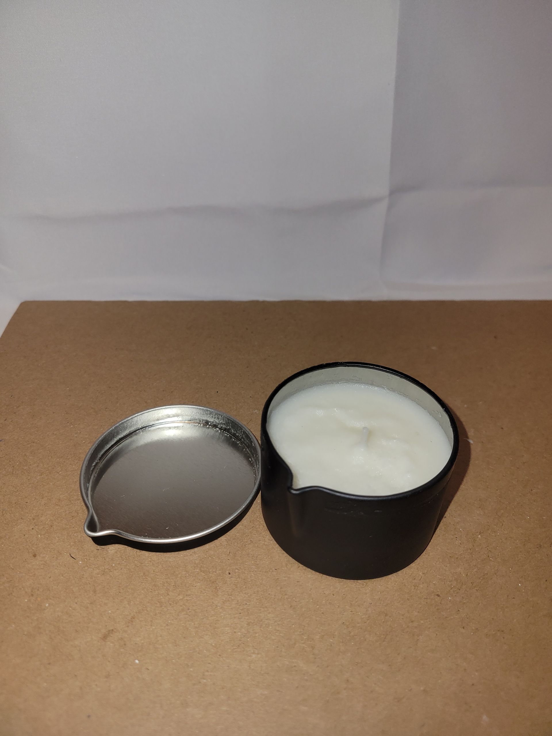 Black candle in a small glass holder on a brown surface.