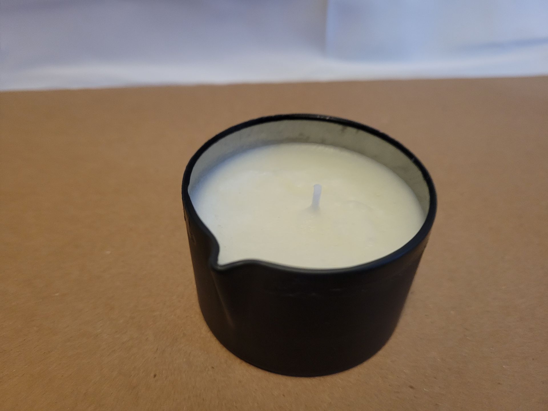 Black candle in a small glass holder on a brown surface.