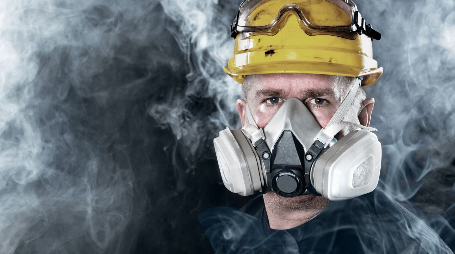 A man wearing a gas mask is surrounded by smoke.