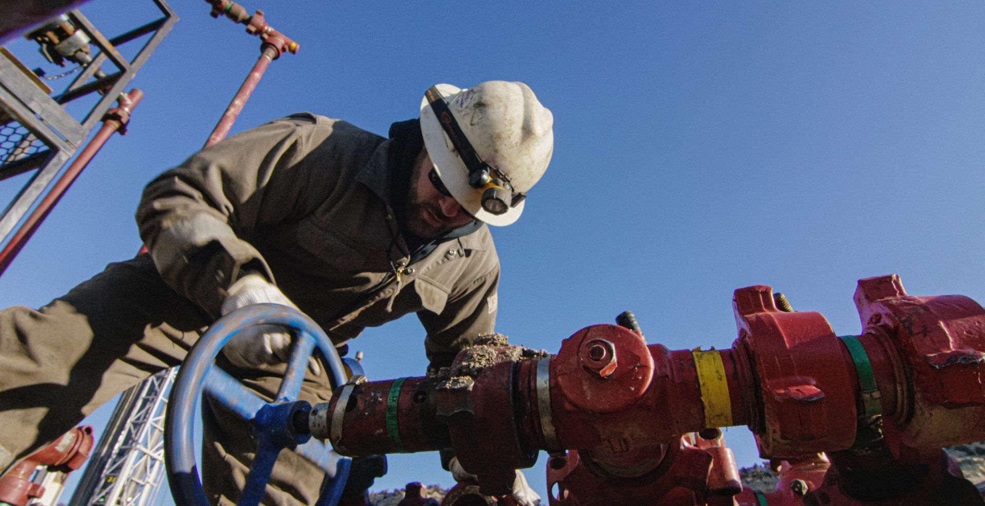 A man working on a hydraulic pipe valve.