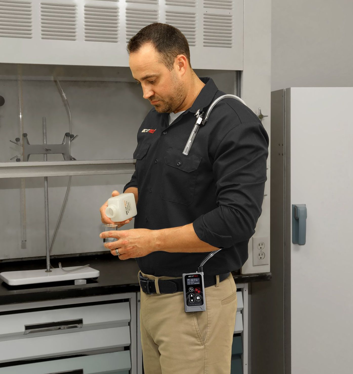 A man is working in a lab while wearing Nextteq®'s NEW NX-300 constant flow, low flow sampling pump.