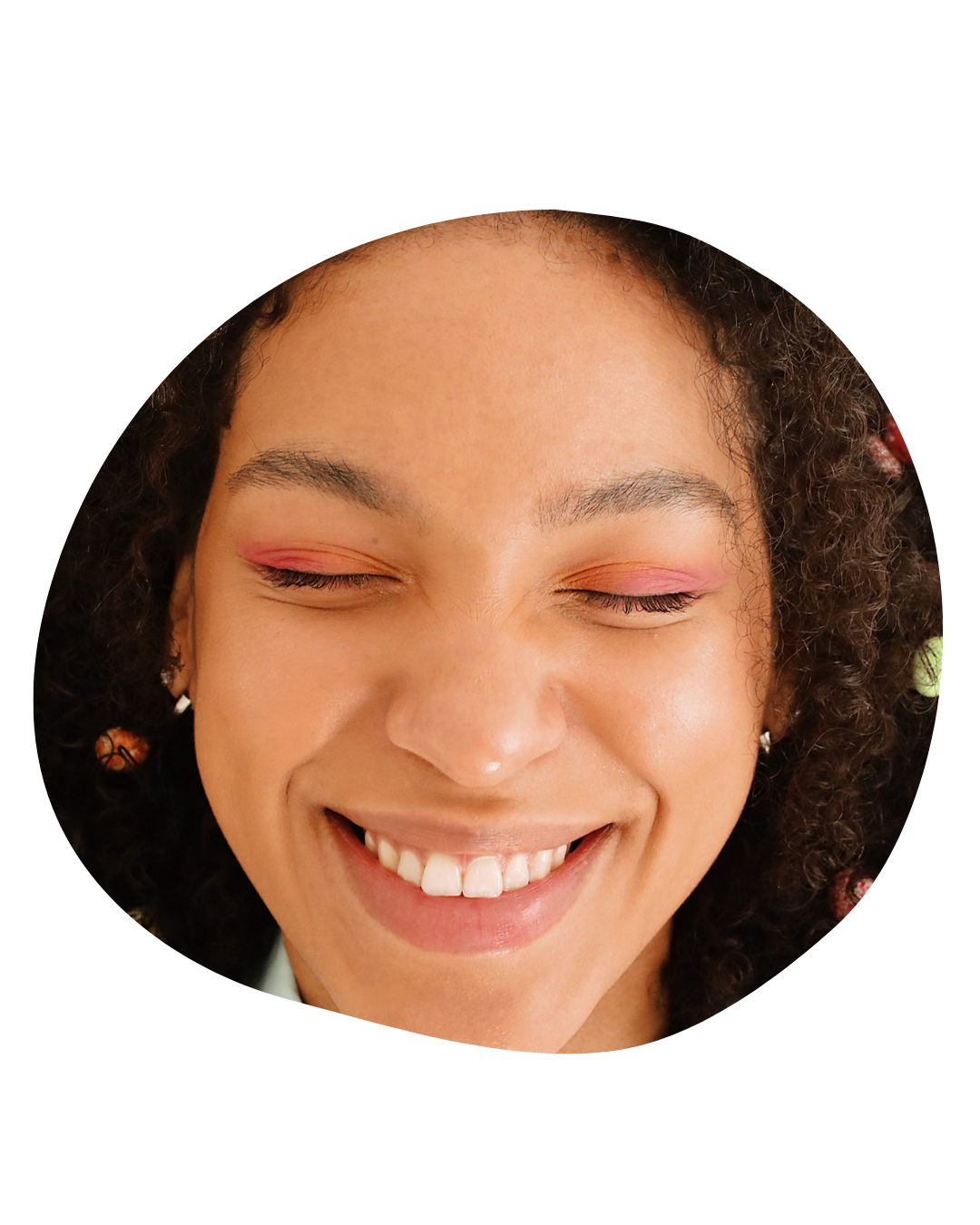 Close-up of a smiling face with closed eyes and subtle pink eye makeup