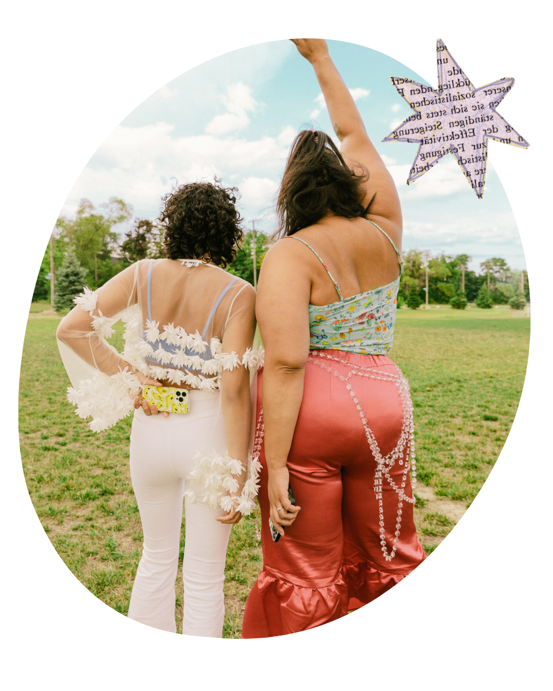 Two women in festive outfits standing in a grassy field, seen from behind under a cloudy sky.