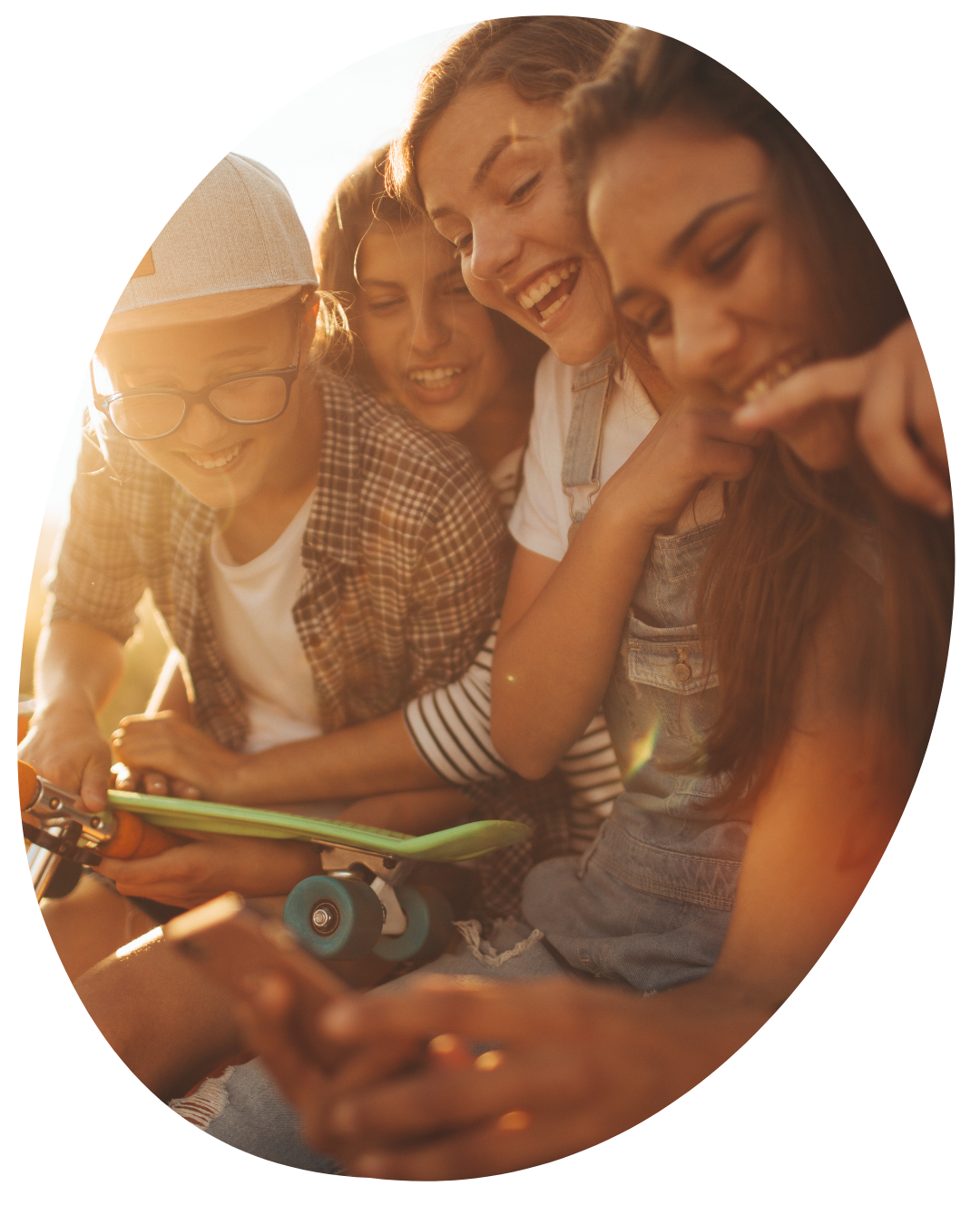 Three people smiling together and looking at a tablet in warm sunlight