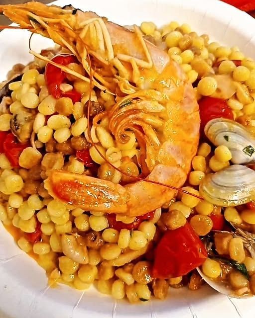 Pasta ai frutti di mare con gamberetti, cozze, ceci e pomodorini in una ciotola bianca